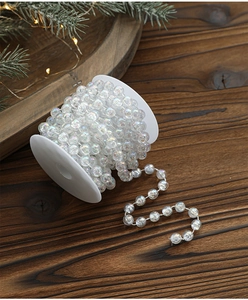 Detailed view of iridescent white acrylic pearl bead chain on a wooden craft table