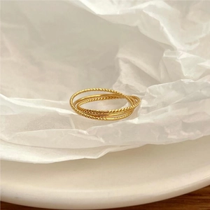Detailed view of 925 sterling silver triple layered golden twisted rope ring on paper