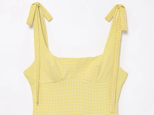 Detail of yellow gingham dress featuring tie-up straps and textured seersucker fabric