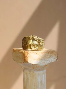 Macro detail of antique gold Venus face relief on a sculptural vintage open ring