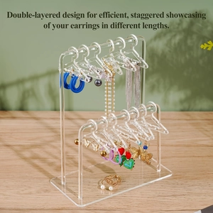 Detail showing tiered acrylic earring rack with miniature hangers on a wooden desk