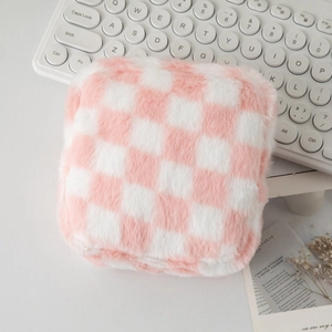Gros plan d'une trousse à cosmétiques en peluche à damier rose et blanc sur un magazine