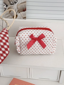 Detail of red heart patterns and bow on a quilted cotton makeup pouch with ruffled edges