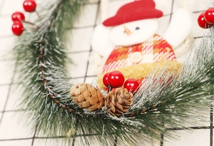 Detail eines Weihnachtskranzes mit Schneemannpuppe, Kiefernnadeln und roten Beeren