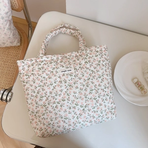 Close-up of quilted floral cotton bag with simple wish label on white table