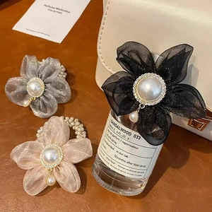 Gros plan de chouchous fleurs en organza avec strass et perles sur fond en cuir marron