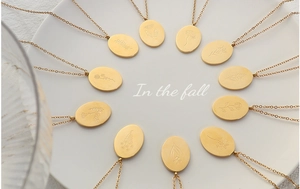 Macro view of twelve assorted gold flower engraved oval pendants on fine link chains