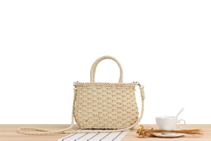 Detailed close-up of a beige straw woven handbag featuring natural textures and metal hooks