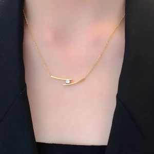 Minimalist gold necklace with parallel curve pendant and diamond, worn on collarbone