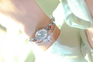 Close-up of silver quartz watch with red gemstones and matching bow bracelet on wrist