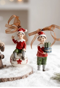 Detail of resin Christmas elf ornaments with gift boxes and star patterns on snow background