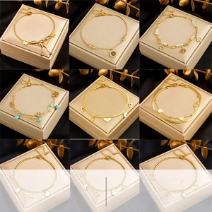 Detailed close-up of nine gold stainless steel anklets with butterfly and tree charms