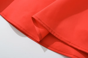 Gros plan détaillé des coutures fines et du tissu rouge lisse sur l'ourlet de la robe