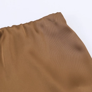 Detailed macro view of the silky brown satin fabric texture with elegant draping folds