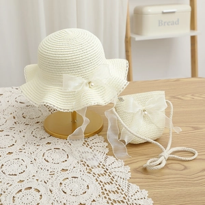 Detailed view of cream straw hat and bag set with organza bows and pearl accents