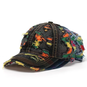 Close-up of vintage distressed denim baseball caps with colorful patchwork and frayed holes