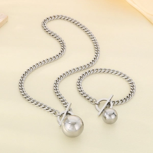 Dettaglio di collana e bracciale a maglia cubana in acciaio argento con pendente a sfera e chiusura OT