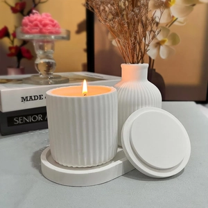 Modern striped ceramic candle jar with matching oval tray and lid on a cozy grey surface