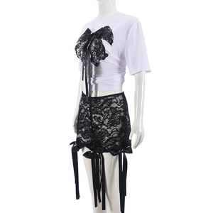 Détail d'un T-shirt blanc avec nœud en dentelle noire et short en dentelle assorti