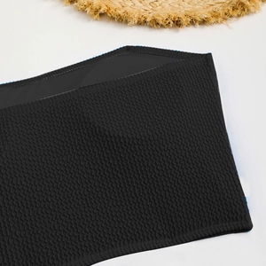Detailed view of black bandeau bikini top with textured seersucker fabric and summer hat
