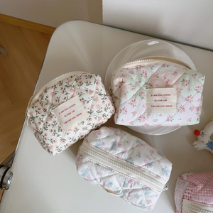 Quilted floral cotton cosmetic bags in pink and green patterns on a white tray
