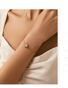 Detailansicht eines Schneeflocken-Anhängers an einem goldenen Armband mit Zirkonia-Steinen