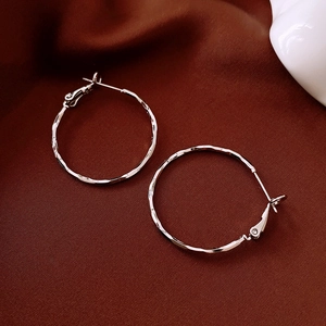 Macro view of silver hammered texture on hoop earrings against brown silk fabric