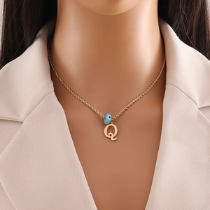 Detail of a gold-plated letter Q pendant with a blue evil eye bead on a choker chain