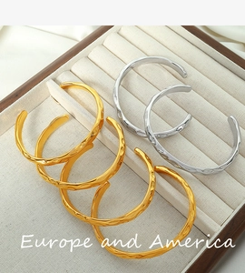 Detail view of gold and silver irregular hammered metal bracelets on a velvet display