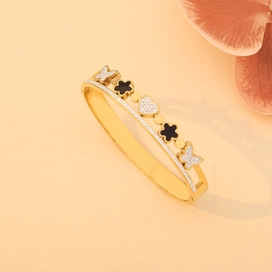 Bracelet doré avec papillons scintillants, trèfles noirs et détail de cœur central