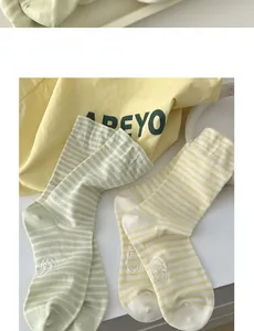 Detail of striped cotton crew socks with brand label in cream and soft green colors