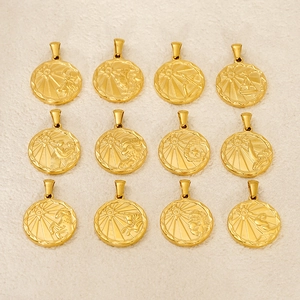 Flat lay of twelve gold zodiac sign pendants with sunburst patterns on beige fabric
