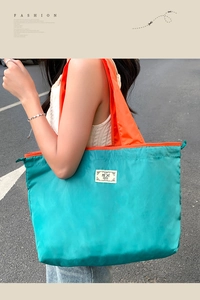 Detail of blue nylon tote bag with orange handles and drawstring closure detail