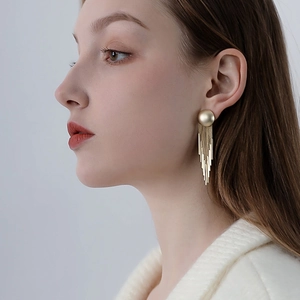 Detailed view of long gold tassel earrings on a model showing metallic texture