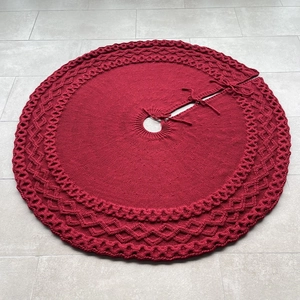 Detail of red knitted Christmas tree skirt featuring diamond mesh pattern and wavy edges