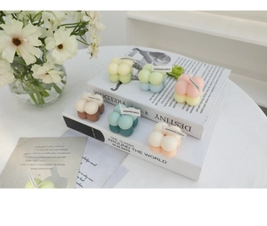 Close-up of colorful bubble cube handmade candles on a white table with floral decor