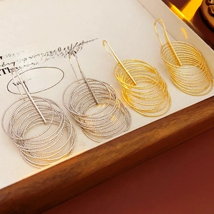 Close-up of layered circular metal earrings with spiral texture in gold and silver finish