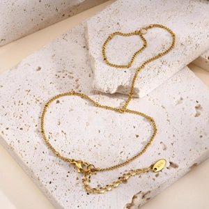 Detail of gold layered snake chain bracelet with beads and lobster clasp on stone base