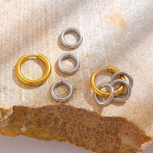 Polierte zweifarbige Creolen in Gold und Silber auf natürlichem Steinhintergrund