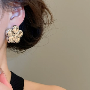 Close-up of silver flower stud earrings with a polished mirror finish on model's ear