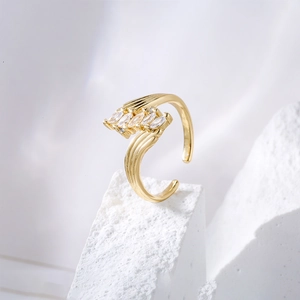 Irregular 18K gold plated ring with marquise zircons displayed on a textured stone