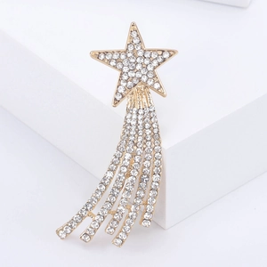 Sparkling gold star brooch with rhinestone tassels displayed on a white podium