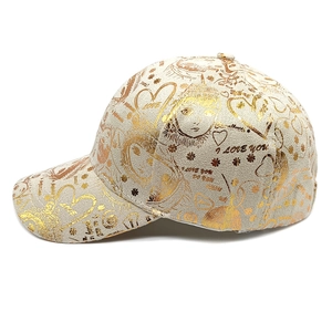 Detail of beige baseball cap with gold metallic graffiti prints and heart patterns