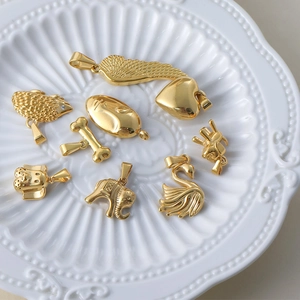 Detailed close-up of 24k gold-plated mixed charms on a white ceramic display plate