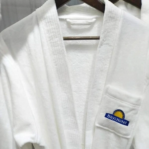 Close-up of white plush hotel bathrobe with blue Days Hotel logo embroidery on pocket