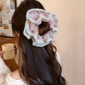 Detail of hand-knitted floral scrunchie in pink and green yarn worn on ponytail