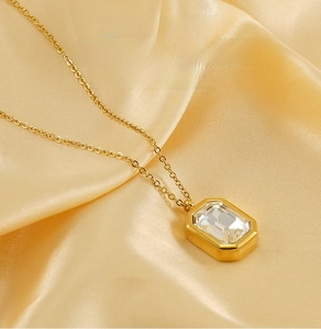 Detail shot of a gold stainless steel necklace with square zircon on champagne silk
