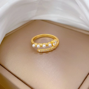 Detailed close-up of gold ring featuring elegant pearls and zircon stones on silk fabric