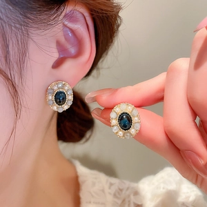 Detail of baroque vintage earring featuring an oval blue gemstone with faux pearls