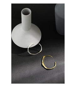Detail of minimalist irregular wavy S925 silver bangles in matte gold and silver finish
